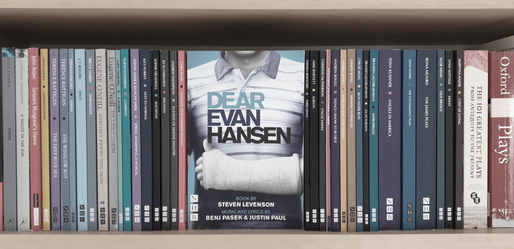 A bookshelf filled with various play scripts. The central focus is "Dear Evan Hansen" by Steven Levenson with music and lyrics by Benj Pasek and Justin Paul.