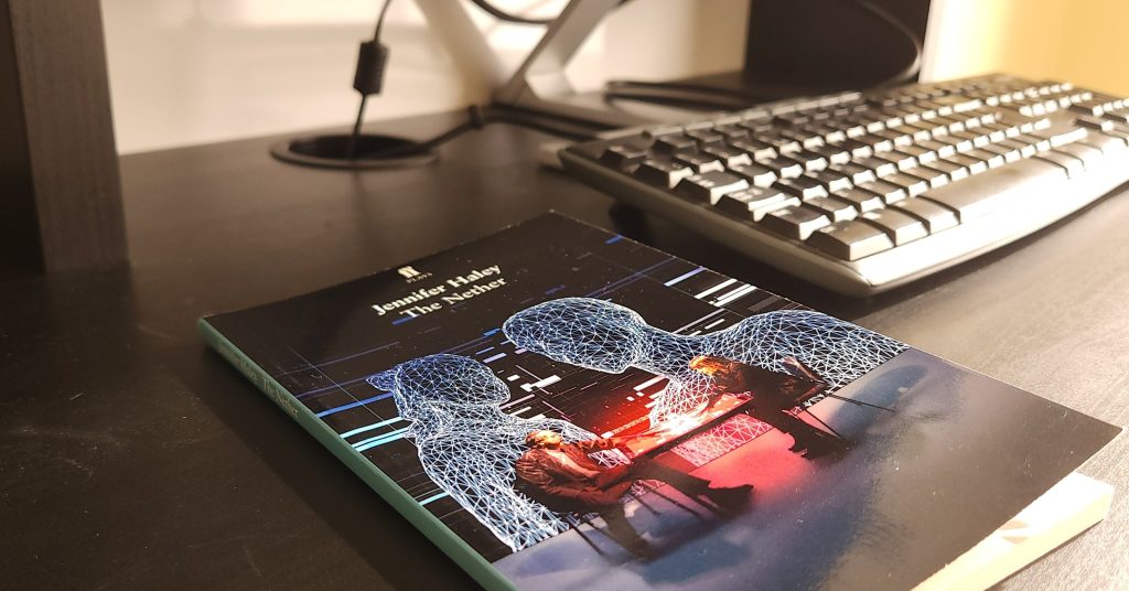 A copy of the play The Nether by Jennifer Haley on a desk next to a computer keyboard